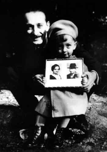 Artur Huppert of Czechoslovakia holds his child, Peterle, and displays the photo of his parents, Rosinka and Jusekl Huppert of Poland, 1941. This visual correspondence between Artur and his parents enables the child, parent, and grandparents to be in the same family portrait despite the challenge of geographical distances. It is probable that it was Rozinka and Jusekl who brought the photos to Auschwitz-Birkenau.